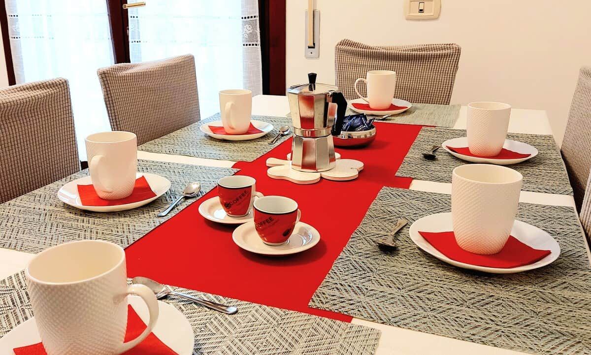 Un coin repas avec une table ronde mise pour un repas, comprenant une cafetière, des tasses et des couverts.