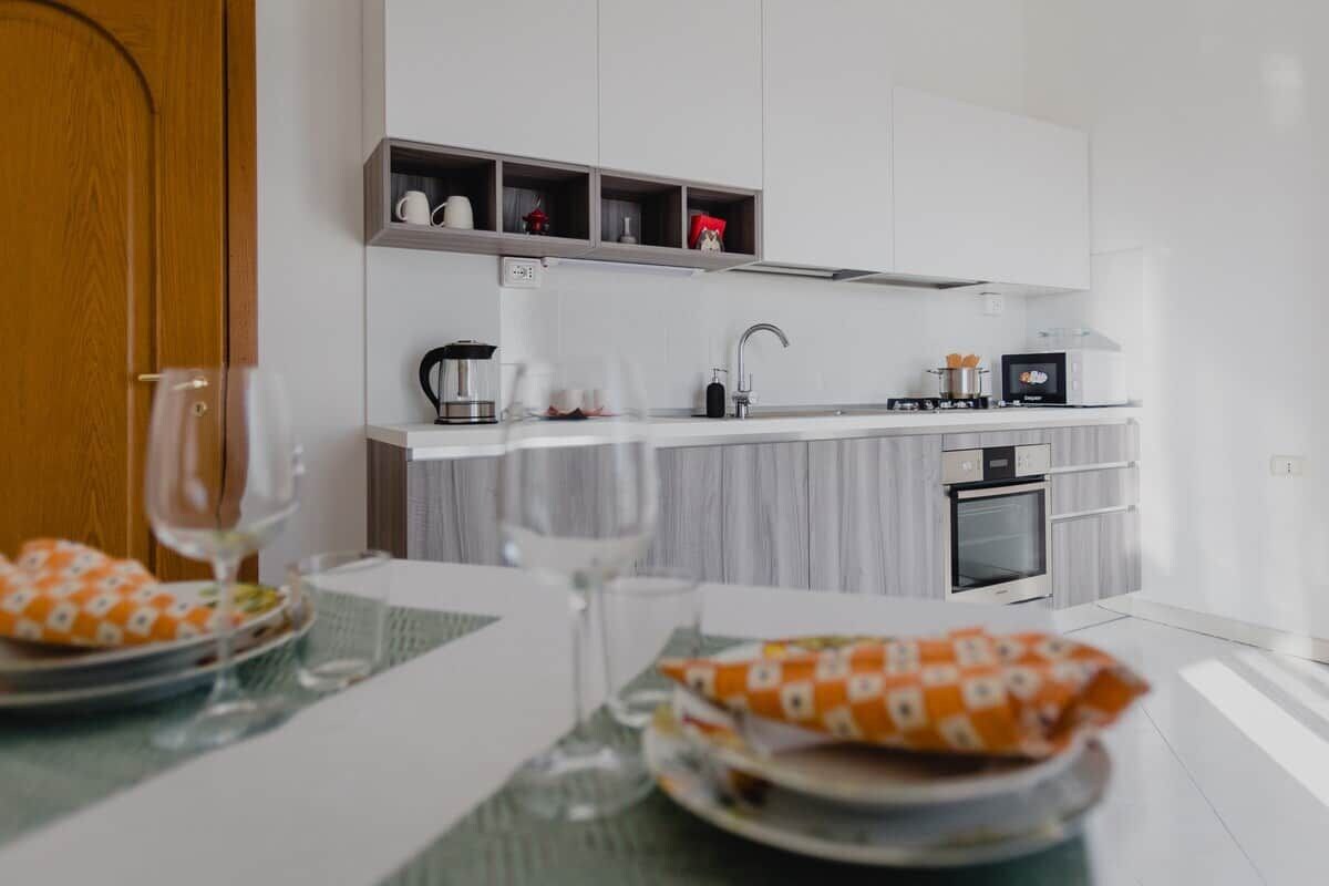 Una cocina moderna con armarios blancos, horno integrado y microondas.