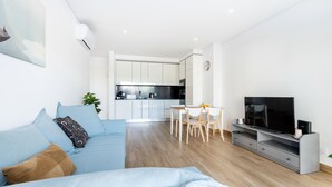Ein modernes Wohnzimmer mit einer Couch, einem Fernseher und einem Essbereich.