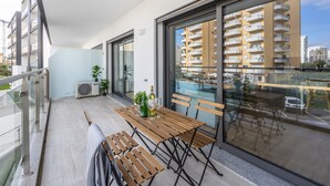 Ein Balkon mit Holztisch und Stühlen, einem Blumentopf und einer Baxi-Klimaanlage.