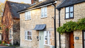 A stone cottage with a green door, white windows, and a small awning. - Forge Cottage - Winchcombe, Cheltenham, a charming Cotswolds property sleeping 4 guests (Winchcombe)