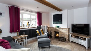 A cozy living room with a fireplace, a television, and comfortable seating. - Forge Cottage - Winchcombe, Cheltenham, a charming Cotswolds property sleeping 4 guests (Winchcombe)