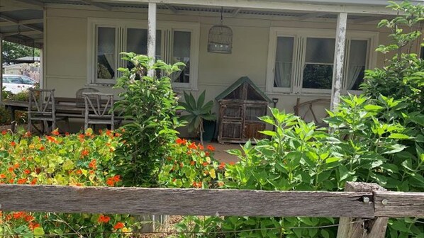 Ein Haus mit einer Veranda, einem Vogelkäfig und einem Holzzaun.