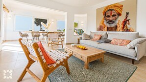 Een ruime woonkamer met een bank, salontafel en een eethoek.
