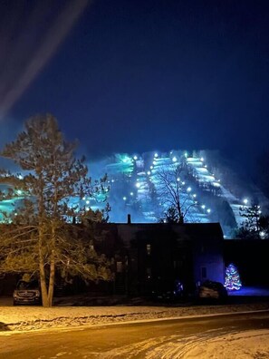 Schneebedeckte Landschaft mit einem beleuchteten Bauwerk im Hintergrund.