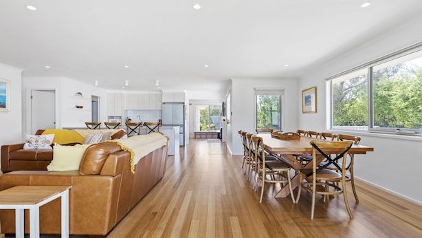 A spacious living area with a brown leather sofa, wooden dining table, and chairs. - Cosmopolitan Sorrento (Sorrento)
