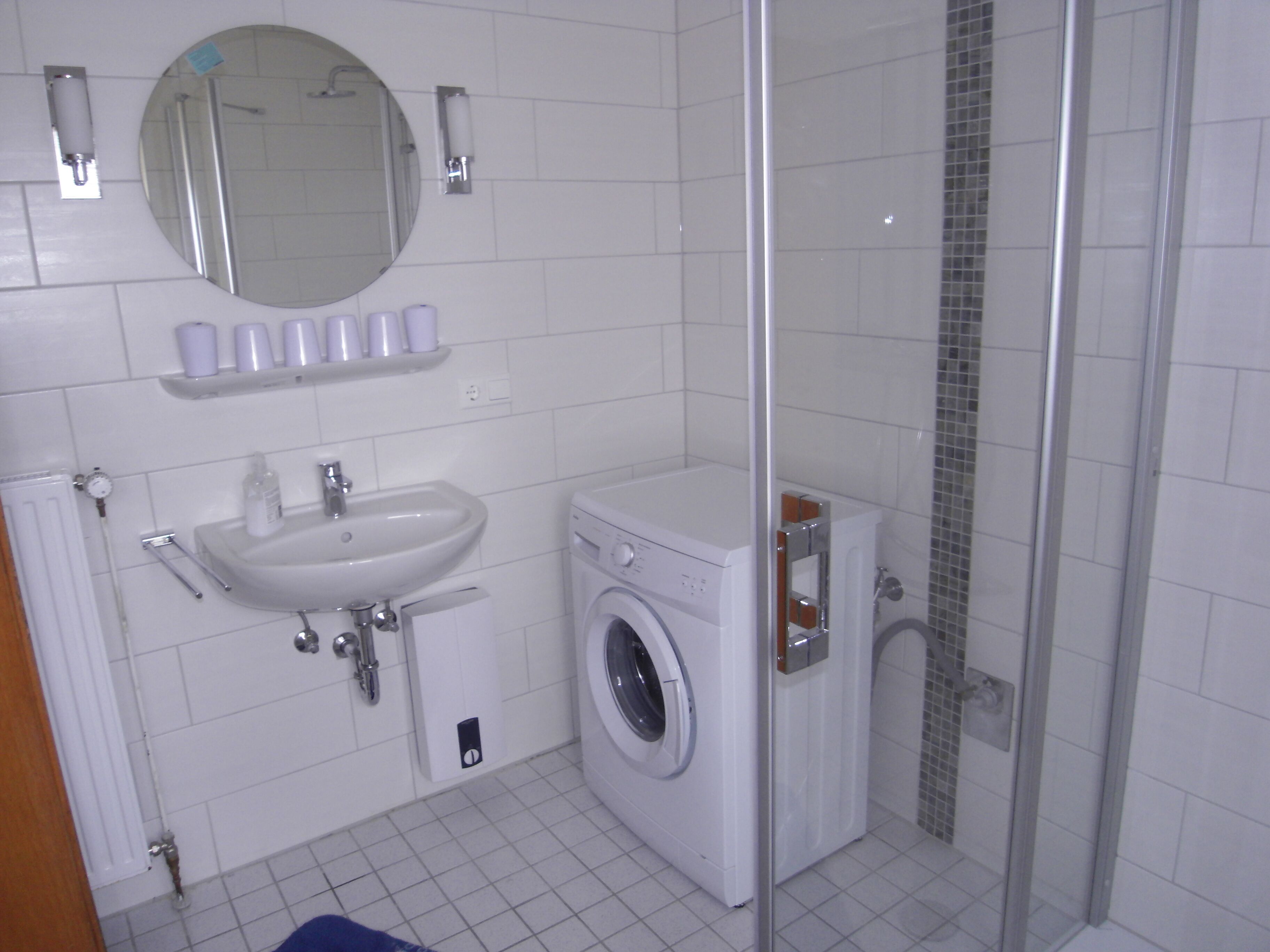 Un baño con lavamanos, espejo y lavadora.