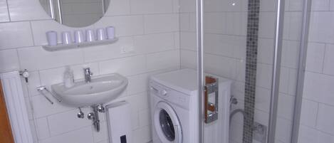 Un baño con lavamanos, espejo y lavadora.