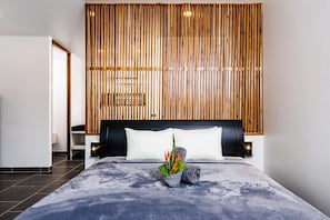 Une chambre à coucher moderne avec un grand lit, un mur recouvert de lambris en bois et une table de chevet avec une lampe.