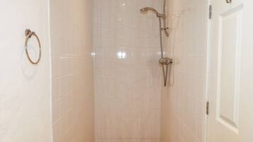 Un pequeño baño revestido con azulejos, con un cabezal de ducha y un aro para toallas en la pared.