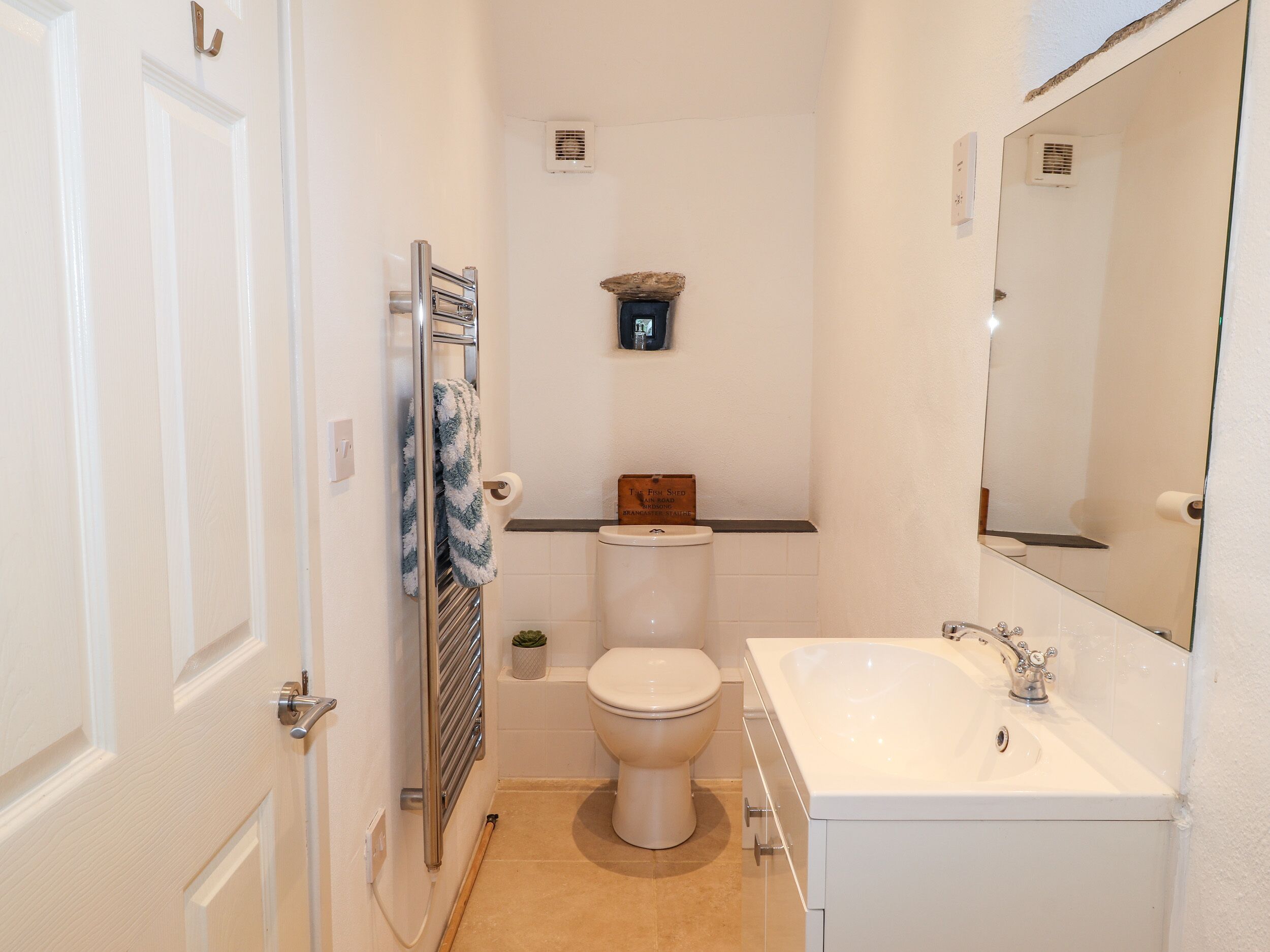 A compact bathroom with a toilet, sink, and towel rack.