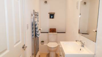 A compact bathroom with a toilet, sink, and towel rack.