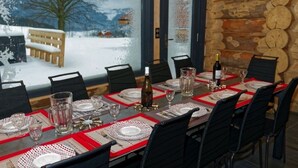 A dining area with a long table set for six, featuring red placemats and clear glassware.