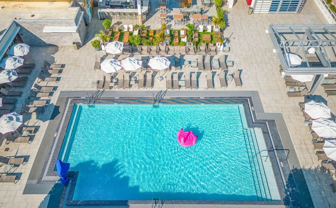 A rooftop pool with clear blue water, surrounded by lounge chairs and umbrellas.
