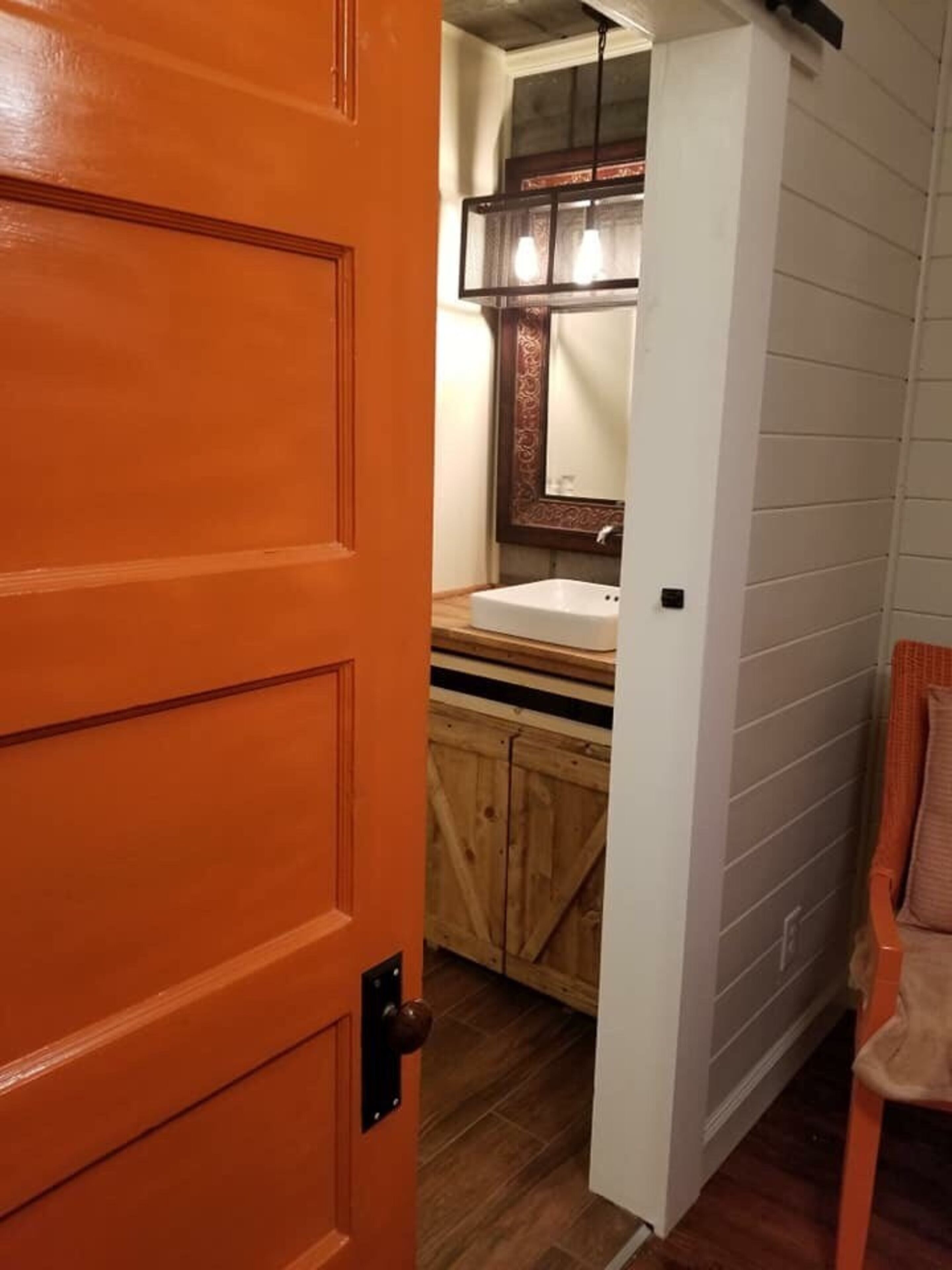 A bathroom with a wooden cabinet, a white sink, and a mirror with a decorative frame.
