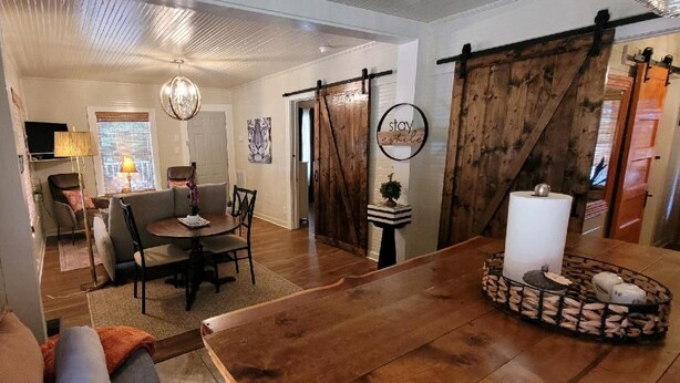 A cozy living room with a fireplace, a dining area with a table and chairs, and a large wooden door. - Clemson Memorabilia House (Clemson)