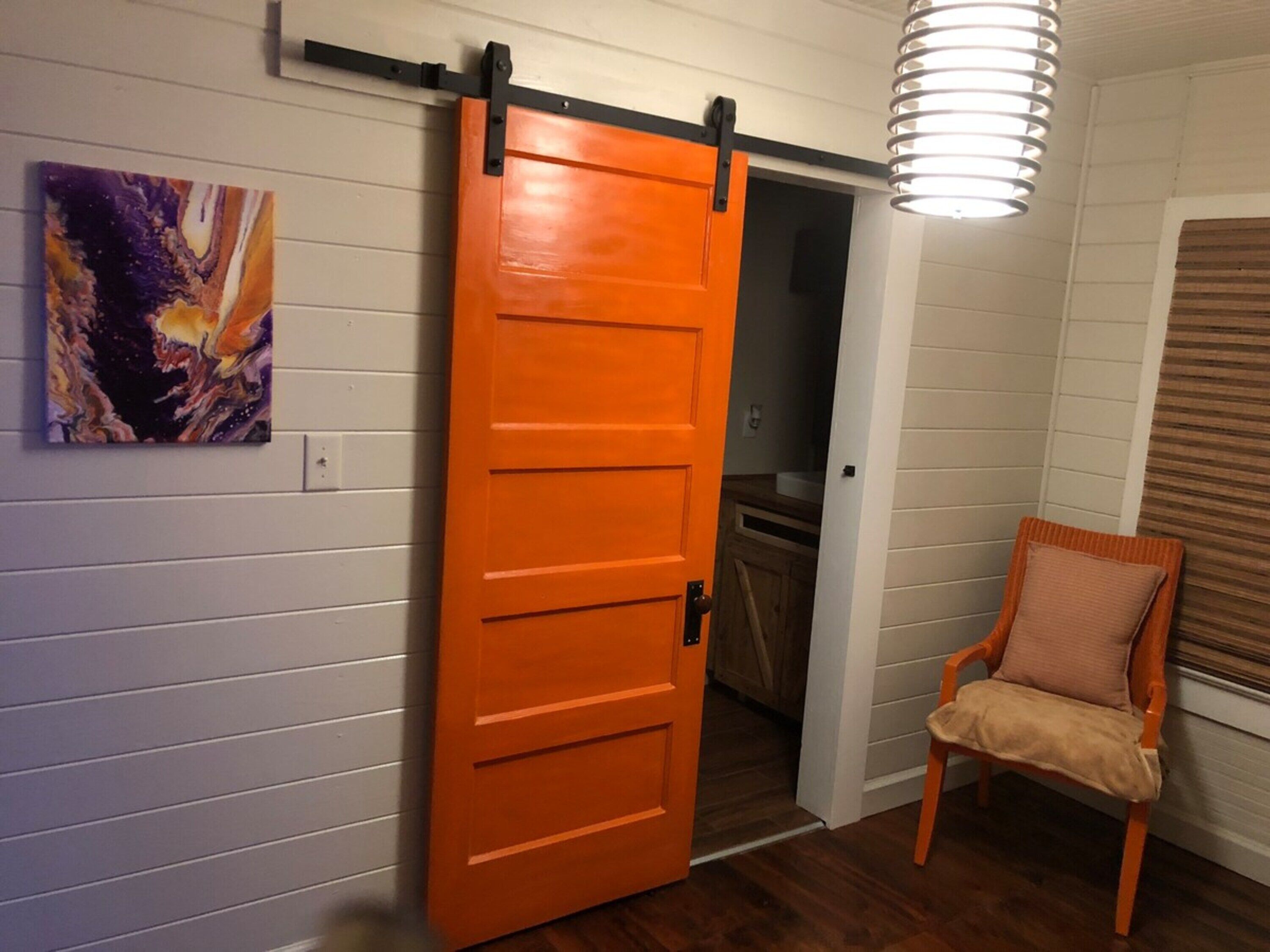 Una habitació amb una porta corredissa, una cadira i un llum penjant.