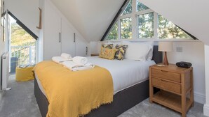 Un dormitorio con cama, mesita de noche, lámpara y ventana.