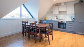 Una cocina moderna con comedor, que incluye una mesa y sillas de madera, un ventanal grande y armarios grises.