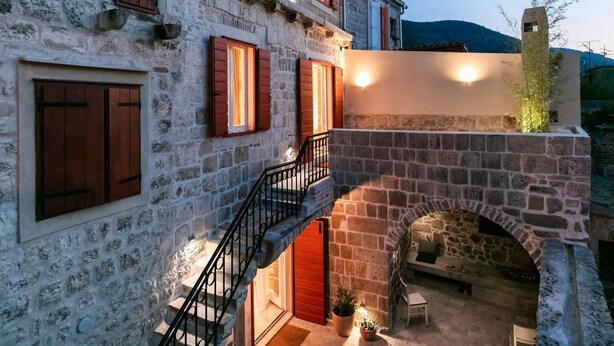 Un bâtiment en pierre avec un escalier menant à un espace extérieur abrité.