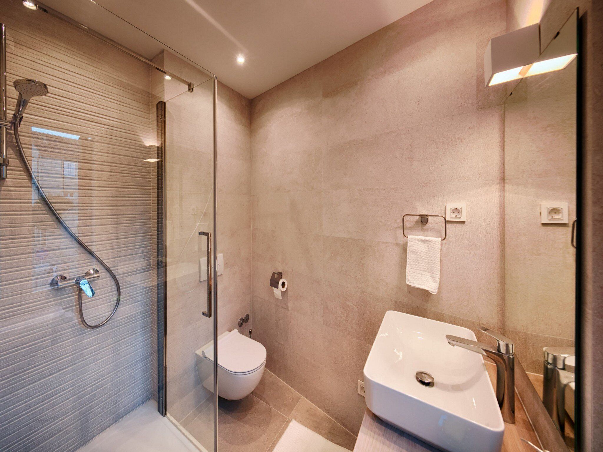 A modern bathroom with a glass shower enclosure, a toilet, and a sink with a mirror.