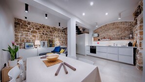 Une cuisine moderne avec des armoires blanches, un mur d’accent en pierre et un four encastré.