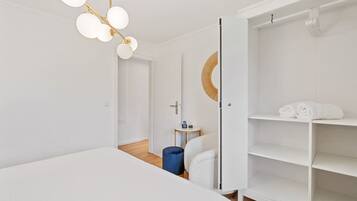 A modern hotel room with a large bed, a wardrobe, a small side table, and a unique circular mirror.