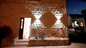 Un edificio con fachada de piedra y una ventana pequeña con contraventanas.