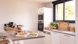 Una cuina moderna amb una illa de fusta, electrodomèstics integrats i un gran finestral que proporciona llum natural.