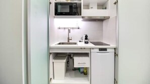 Een kleine keuken met een magnetron, gootsteen en een kleine koelkast.