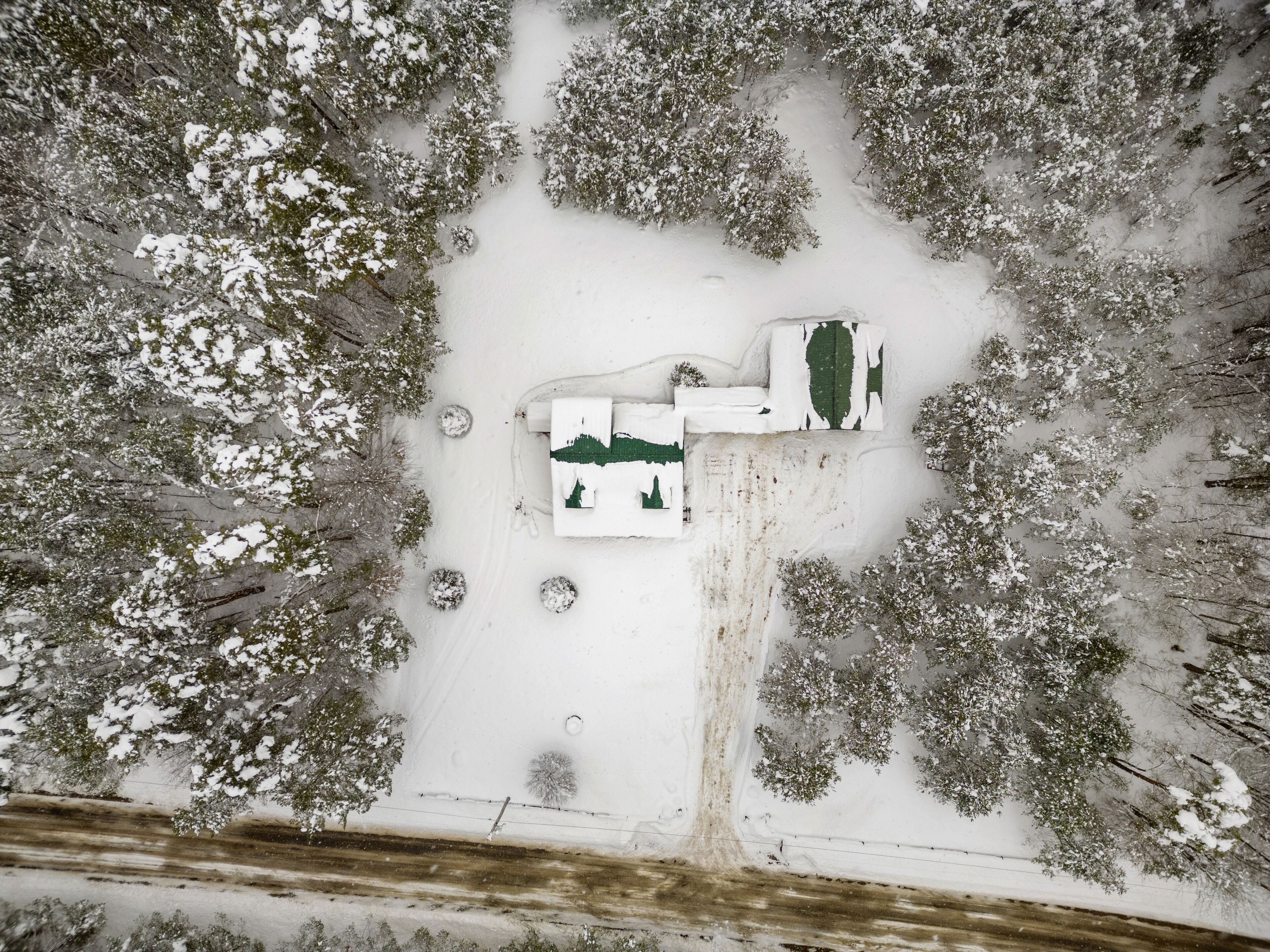 An aerial view of a snow-covered landscape with a building featuring a green roof and white walls.