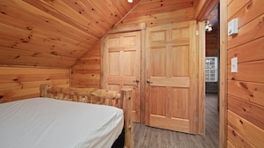 A wooden cabin room with a bed, wooden wardrobe, and a small table. - Loft In the Pines, On Snowmobile Trail (Boonville)