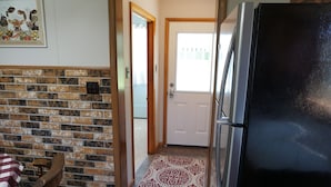 A kitchen with a black refrigerator, a wooden chair, and a patterned rug. - Cozy Farm house 1950's Era but with modern updates (New Enterprise)