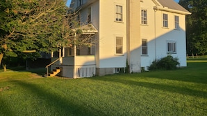 A two-story house with a prominent chimney, a porch, and a well-maintained lawn. - Cozy Farm house 1950's Era but with modern updates (New Enterprise)
