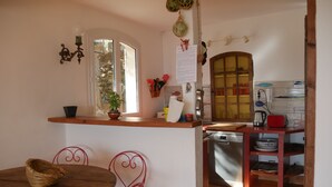 Een kleine keuken met een houten tafel en stoelen, een raam en een koelkast.