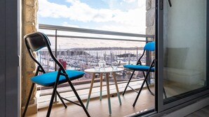 A balcony with two blue chairs and a small round table, overlooking a marina with boats. - Marée Tropicale - vue mer (Saint-Cast-le-Guildo)