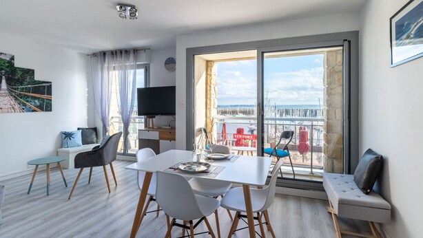 A modern living room with a dining area, large windows, and a view of the sea. - Marée Tropicale - vue mer (Saint-Cast-le-Guildo)