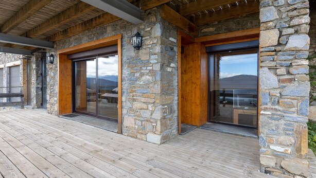 A stone exterior with wooden beams and large glass doors. - Adret - Two Bedroom Apartment, Sleeps 4 (Les Angles)