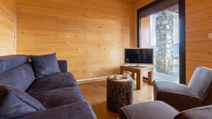 A modern room with wooden walls and a stone pillar, featuring a sofa, a coffee table, and a television. - Adret - Two Bedroom Apartment, Sleeps 4 (Les Angles)