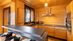 A modern kitchen with wooden walls, a central island, and built-in appliances. - Adret - Two Bedroom Apartment, Sleeps 4 (Les Angles)