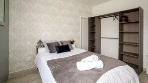A bedroom with a bed, a wardrobe, and a nightstand with a lantern.