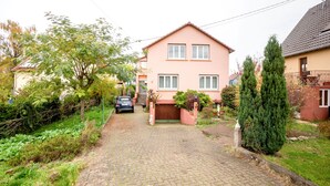 A two-story house with a paved driveway leading to a wooden gate.