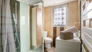 A modern bathroom with a glass shower enclosure, a toilet, and a sink area.