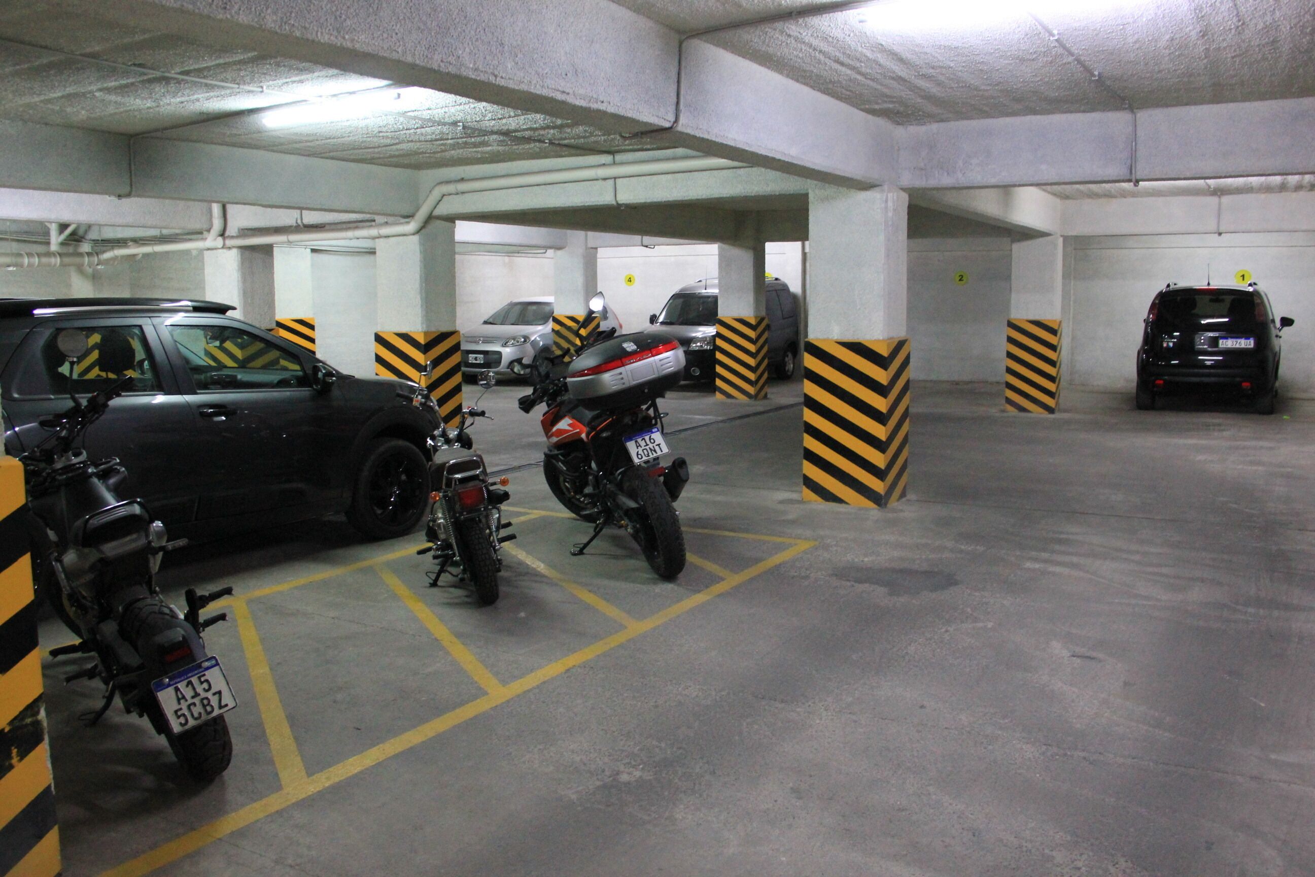A multi-level parking garage with several cars and motorcycles parked.