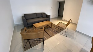 A modern living room with a dark grey sofa, a wooden coffee table, and a woven chair. - HOMEFULL  APARTAMENTOS (Salta)