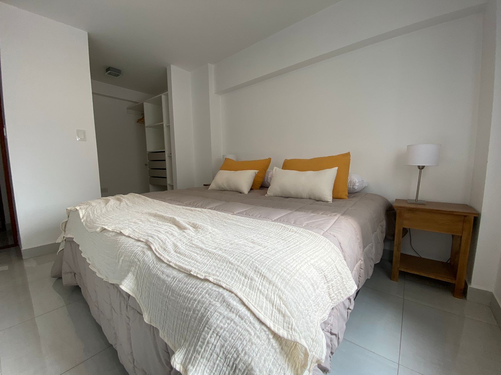 A bedroom with a bed, pillows, a bedside table, and a lamp.