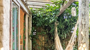 Una pergola in legno con un'amaca, un tappetino di bambù e un pavimento di legno.