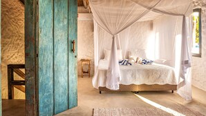 Una stanza con un letto a baldacchino, una porta in legno e un piccolo sgabello di legno.
