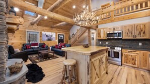 A log cabin interior with a living area, kitchen, and a staircase. - Cabin In the Pines, On Snowmobile Trail (Boonville)