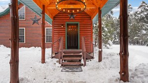A wooden cabin with a star decoration, a green door, and a staircase leading to the entrance. - Cabin In the Pines, On Snowmobile Trail (Boonville)